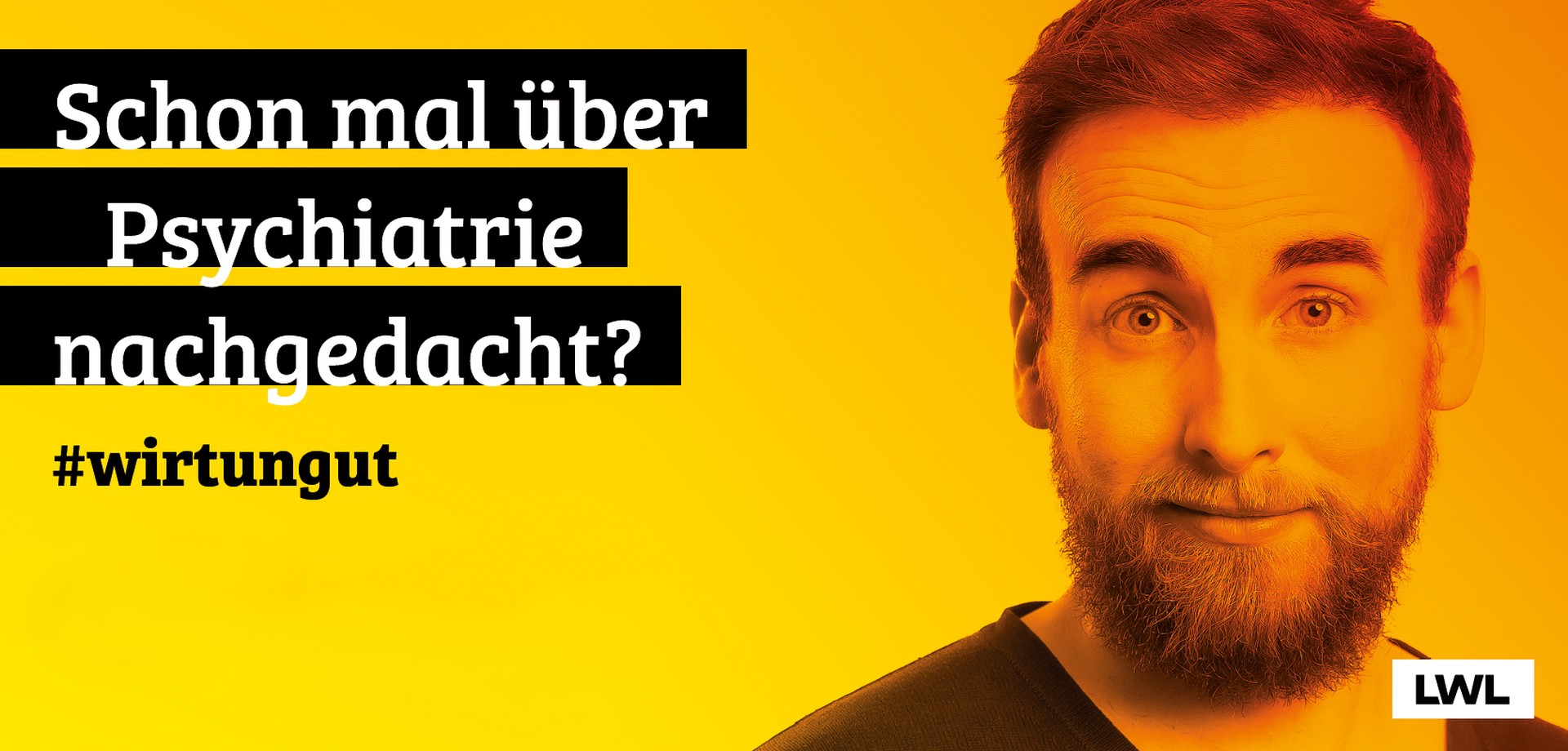 Ein junger Mann mit Vollbart schaut neugierig und nachdenklich in die Kamera