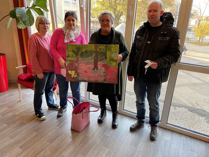 Silke Stiehler (2. v. l.) mit ihrem Ausstellungsbild neben der Kreativtherapeutin Carmen Obermeier (3. v. l.) und weiteren Besucher:innen der LWL-Tage